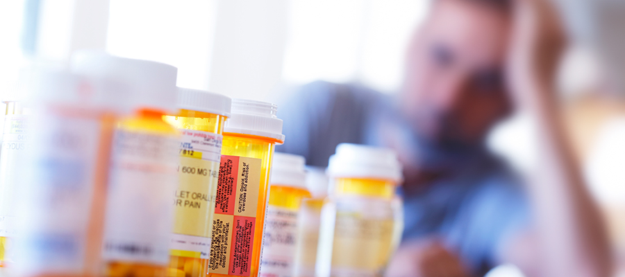 Distraught man sitting in front of prescription medication bottles