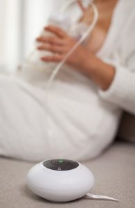 Mother pumps breast milk with electric breast pump.