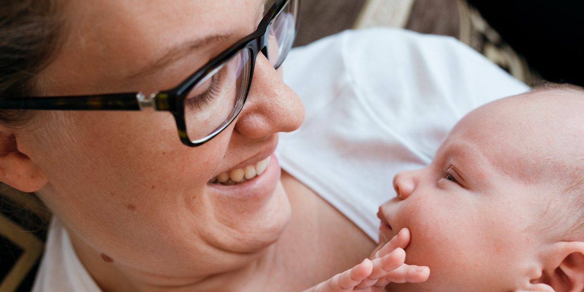 New mom looking at her baby, and wearing glasses.