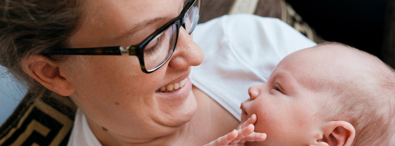 New mom looking at her baby, and wearing glasses.