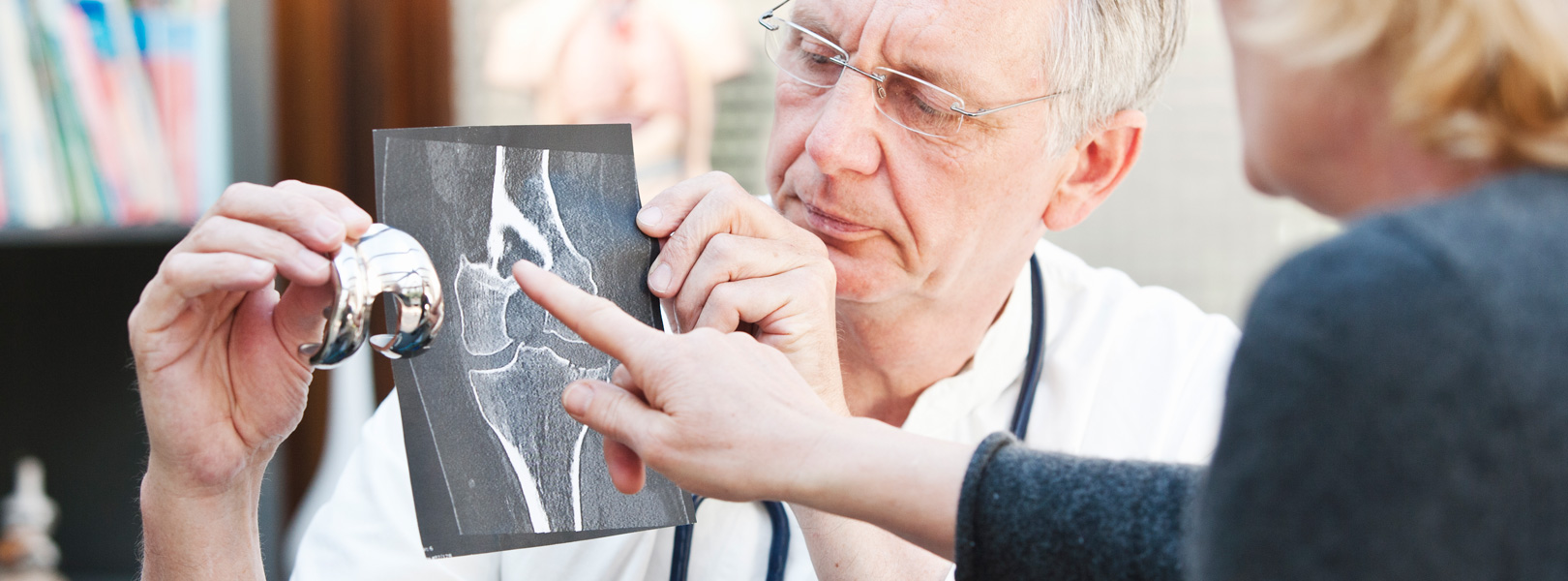 Orthopedic surgeon and patient looking at x-ray and artificial hip