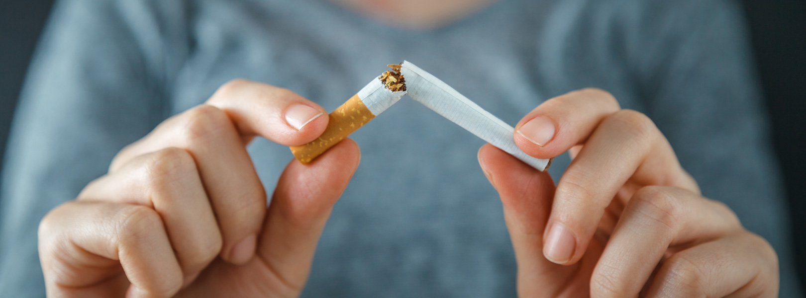 women breaking a cigarette in two