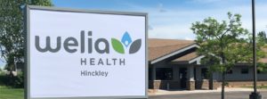 Building sign for Welia Health Hinckley with clinic in background