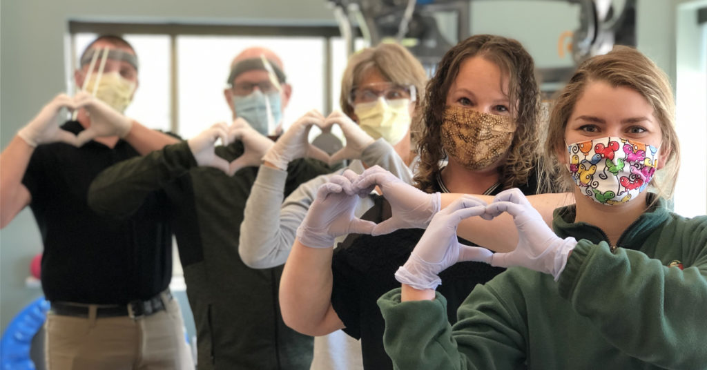 Members of Welia Health Rehab Services team, all forming the shape of hearts with their hands