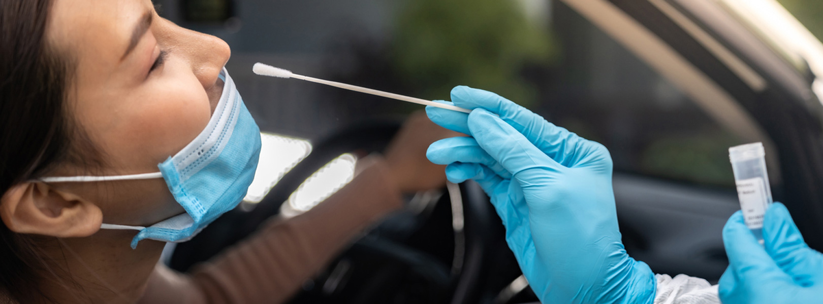 Woman in car getting tested for COVID-19 with nasal swab