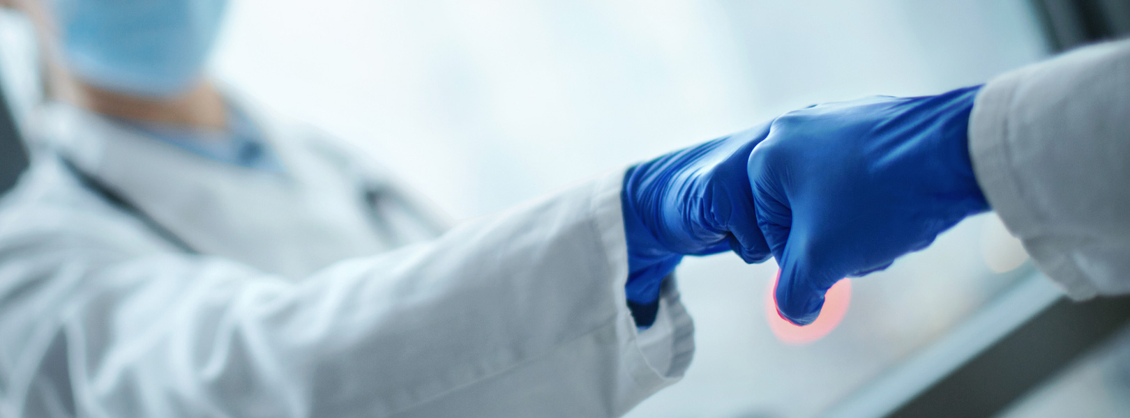 Two healthcare providers in PPE giving a fist bump