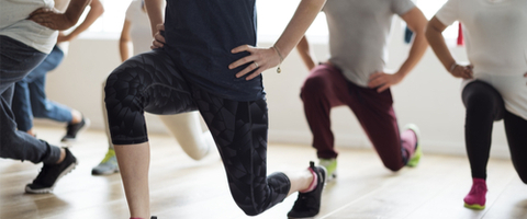 lower body of men and women lunging in an exercise class