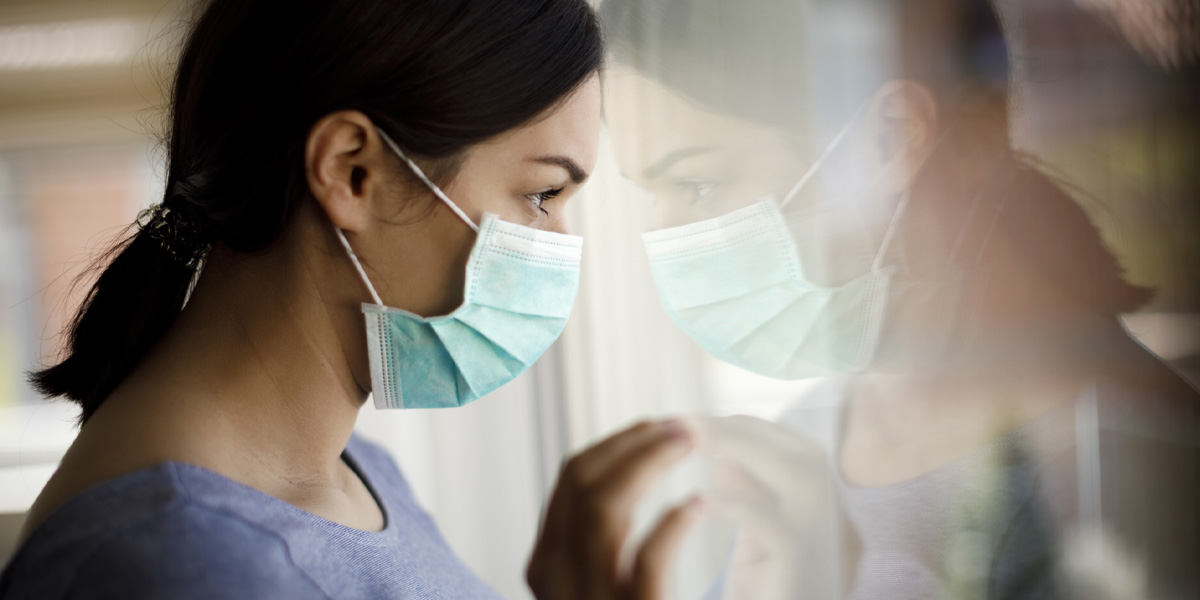 Young women wearing mask looking out the window