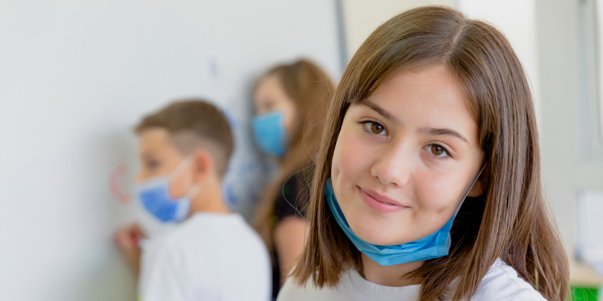 School girl smiling with mask pulled down
