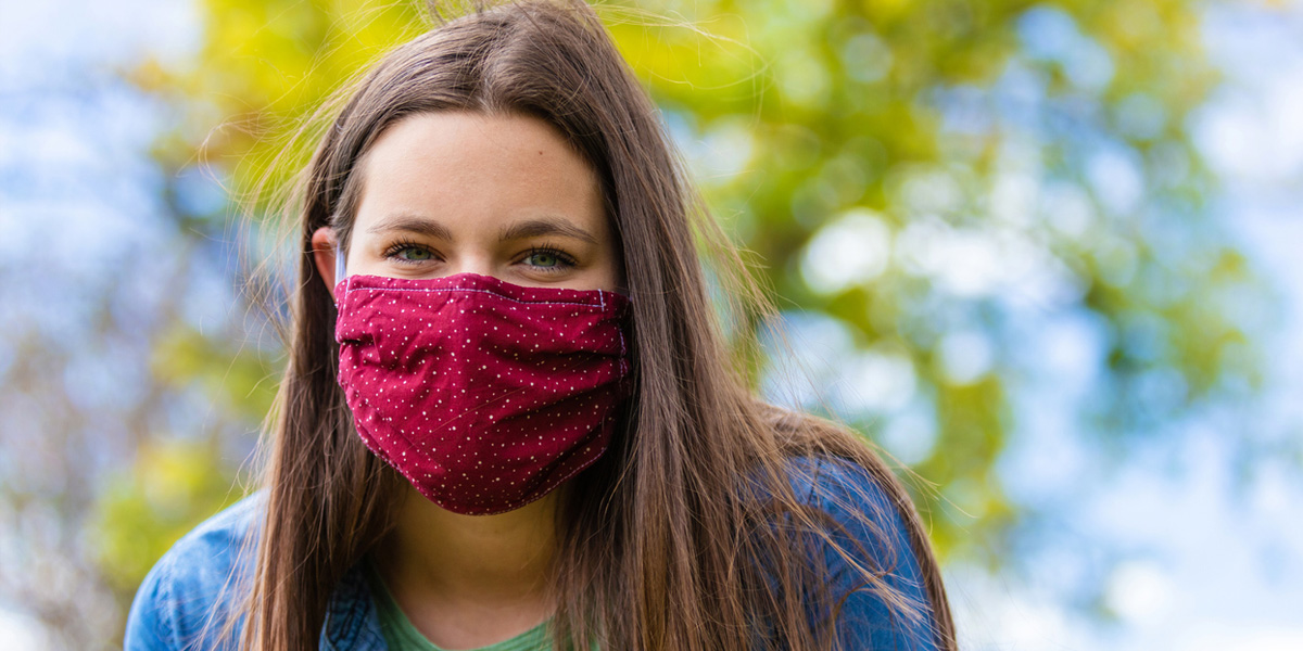 Young woman wearing a mask, sitting outside