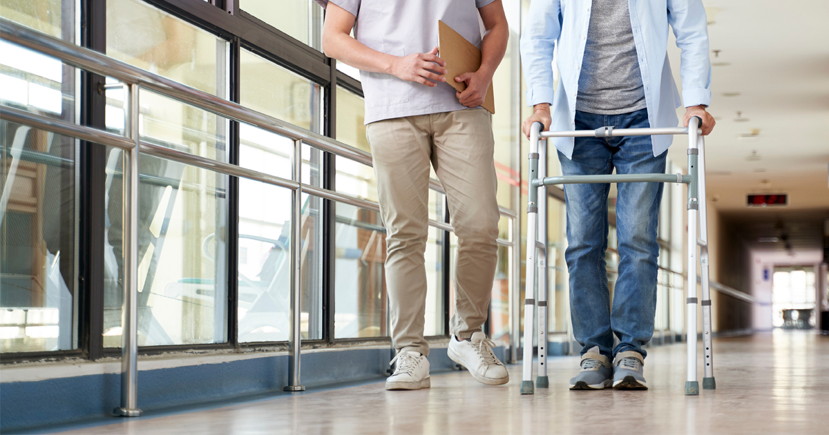 Patient with walker in a long hallway with physical therapist