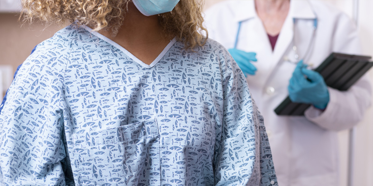 Women in a hospital gown, with face mask and doctor with gloves and stethoscope