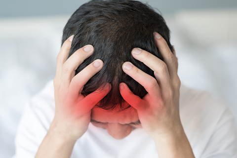 Young man holding his head with red hue near front indicating he has a concussion.