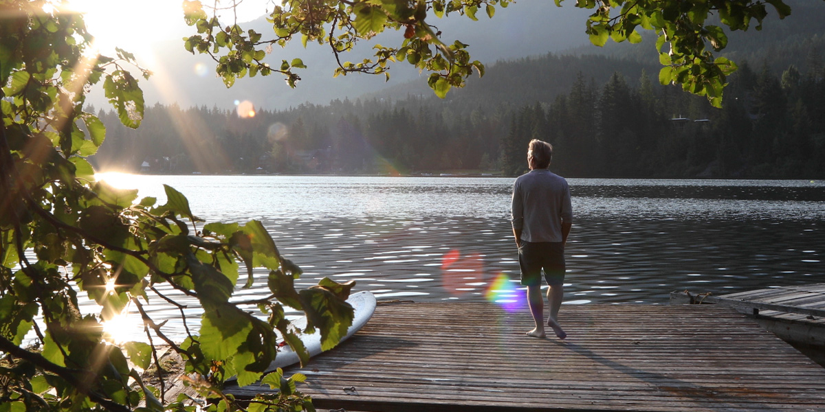 A man standing on a dock next to the lake