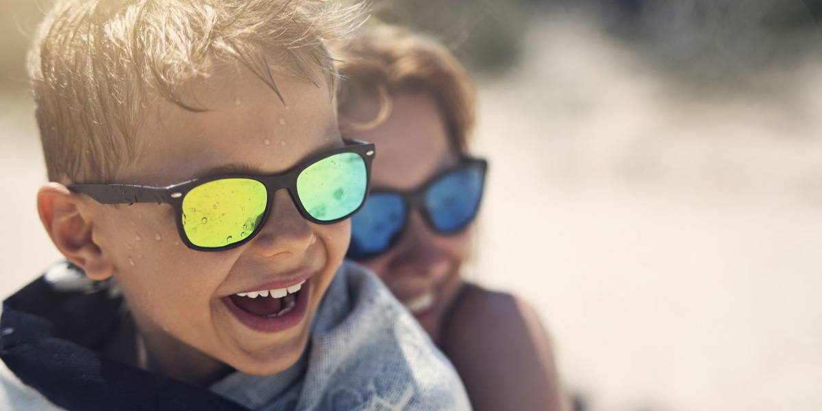 Mother and sun at the beach wearing sunglasses and laughing