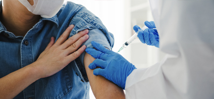 Man with rolled up denim shirt getting a vaccine