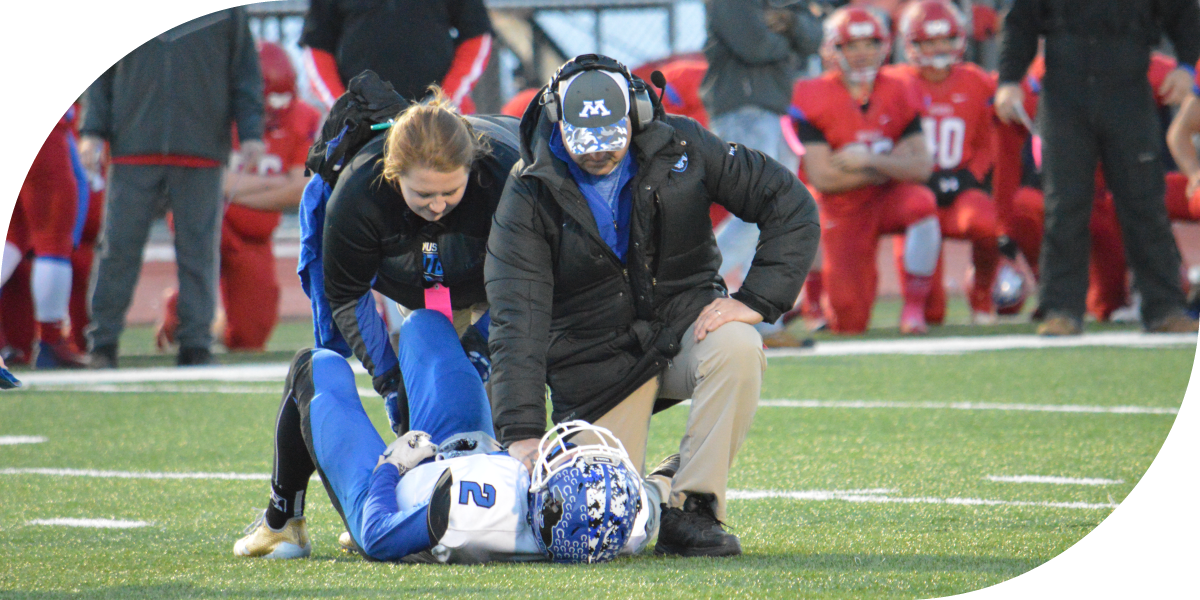 Welia Health athletic trainers evaluating a football player on the field