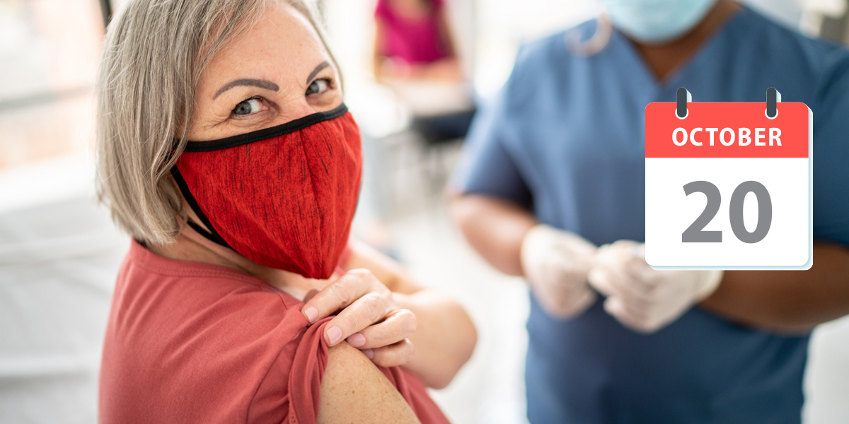 Woman with red face mask rolling up her sleeve for a vaccine