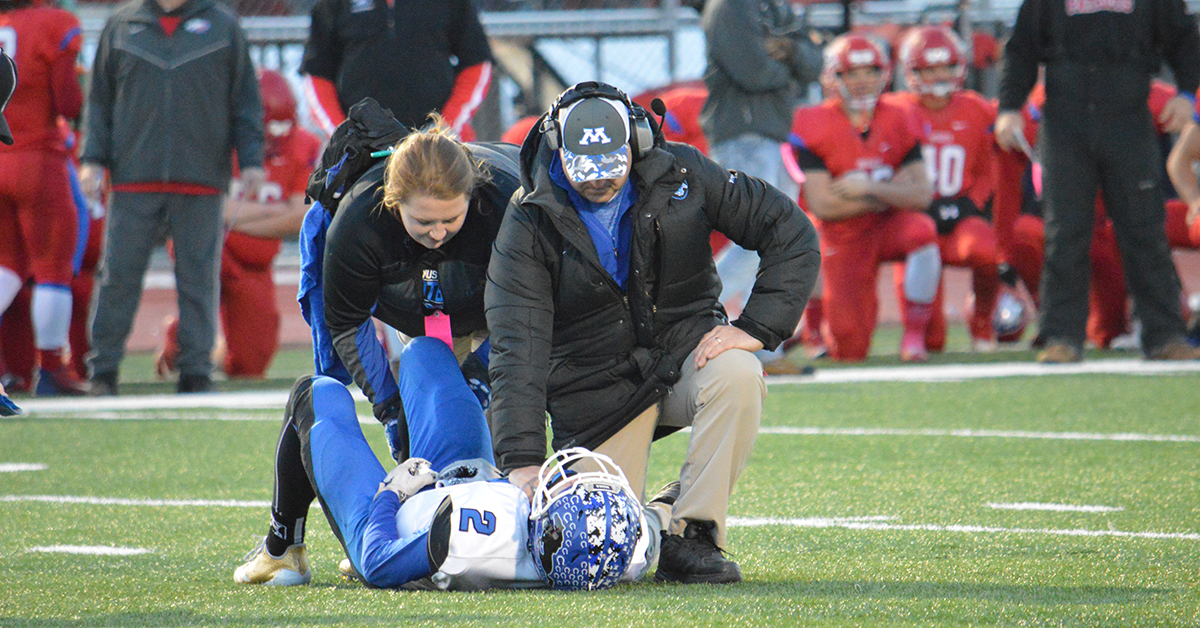 Welia Health athletic trainers evaluating a football player on the field