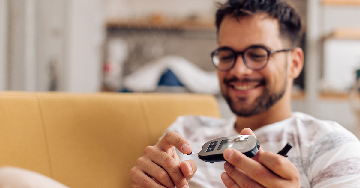 Young man testing his blood sugar with a glucose monitoring device