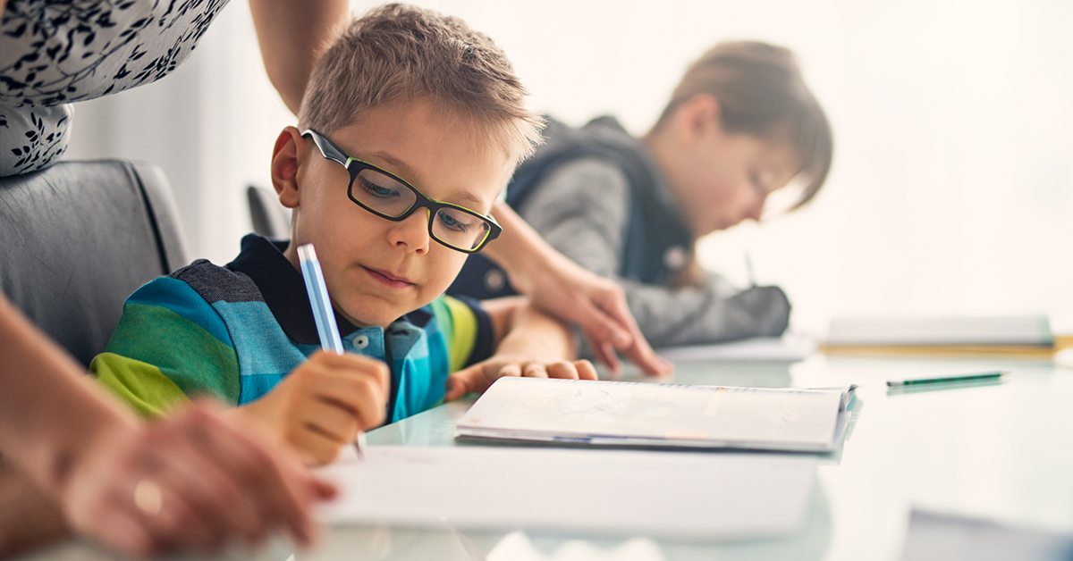 Young boy wearing glasses at his school desk