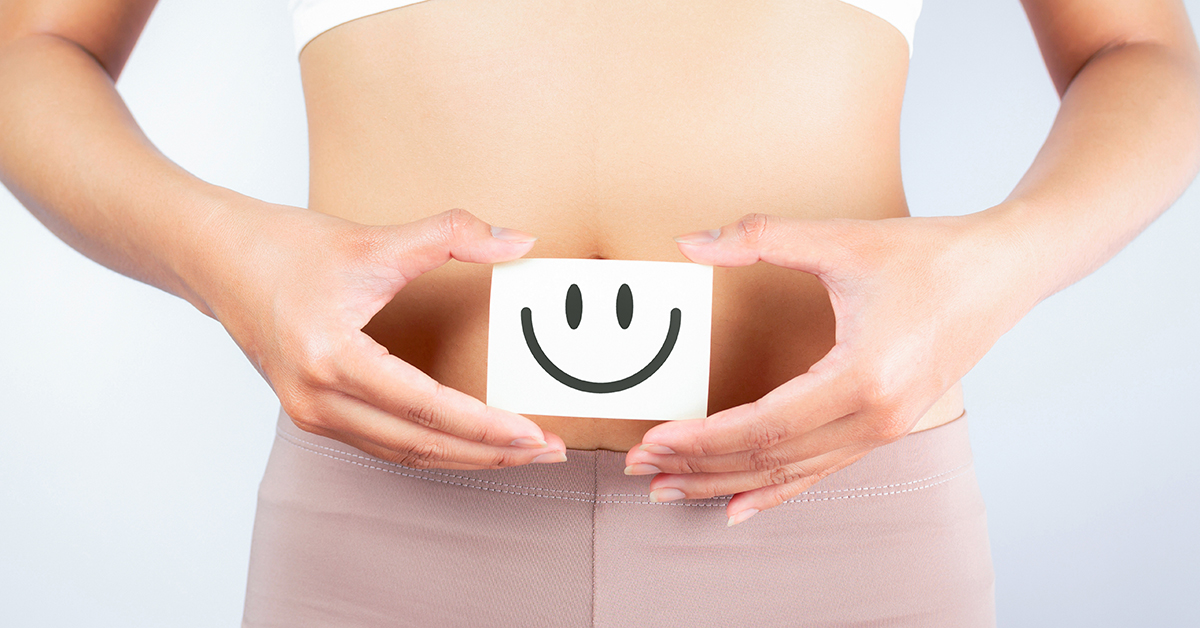 A woman holding a happy face sign in front of the stomach