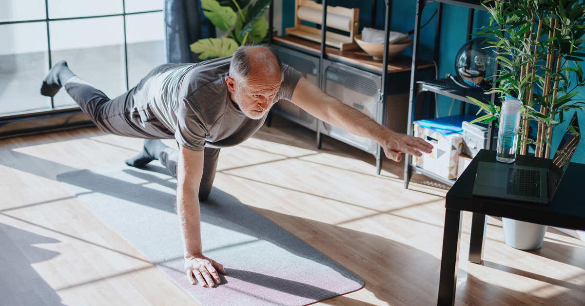 A older man stretching his joint on a yoga mat