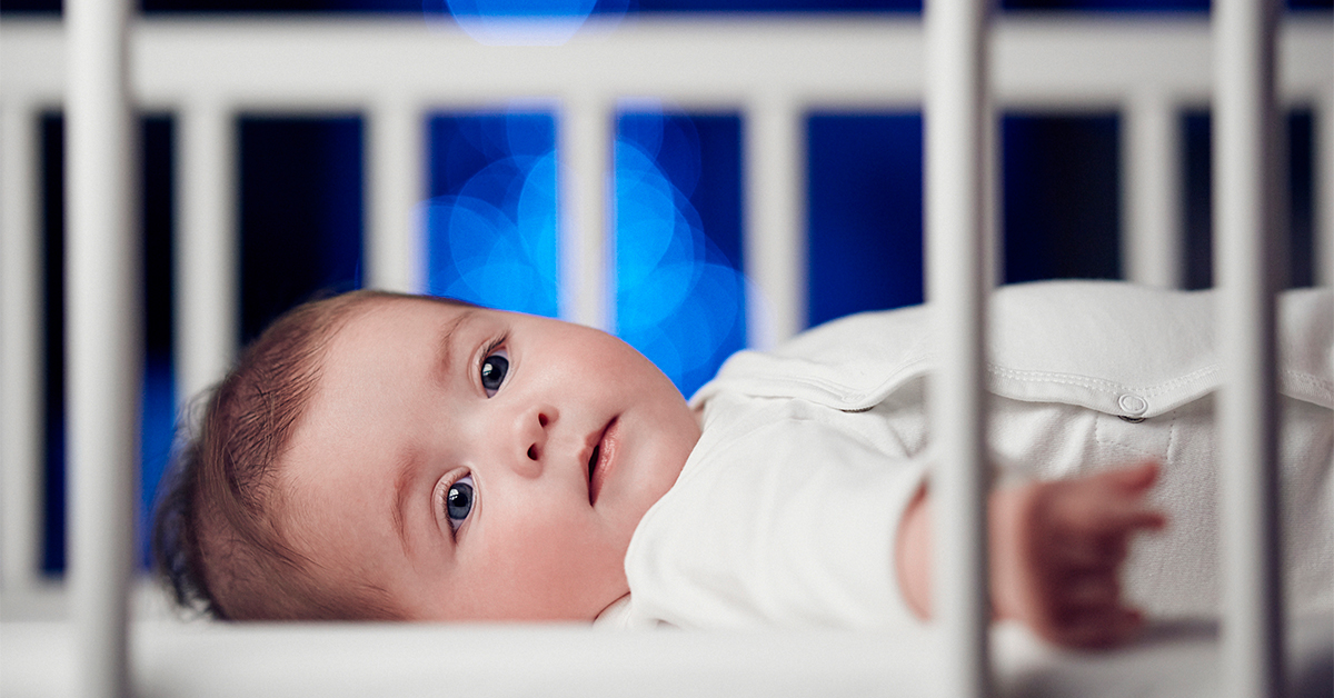 Baby lying on back in a crib