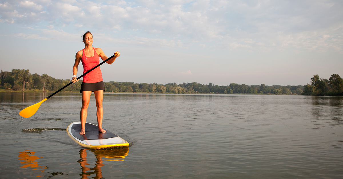 Female standing and paddling on a paddleboard in the middle of a lake