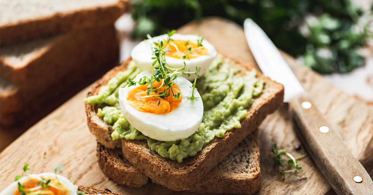 Avocado toast topped with a hard boiled egg and herbs