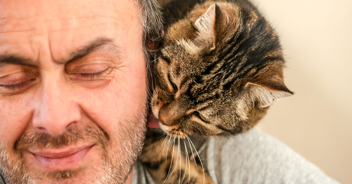 Older man smiling at the cat sitting on his shoulder