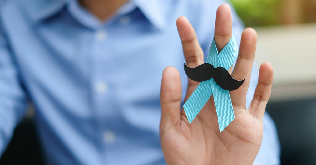 Man hand holding blue ribbon with mustache for supporting 'Movember' to bring awareness to men's health issues
