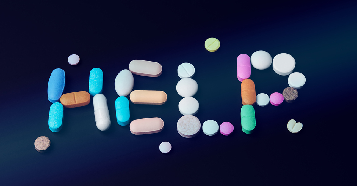 HELP spelled out in pills of different shapes and sizes on dark blue backgournd