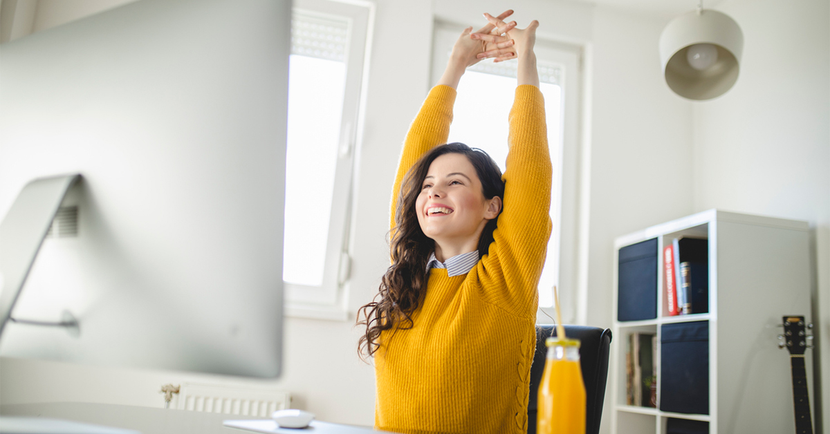 Young women sitting at her desk stretching with arms above her head