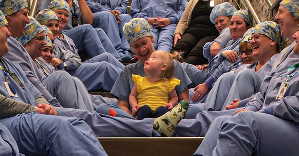 Welia Health OR team members sitting on a staircase with baby Amelia being held by her mother Rebecca