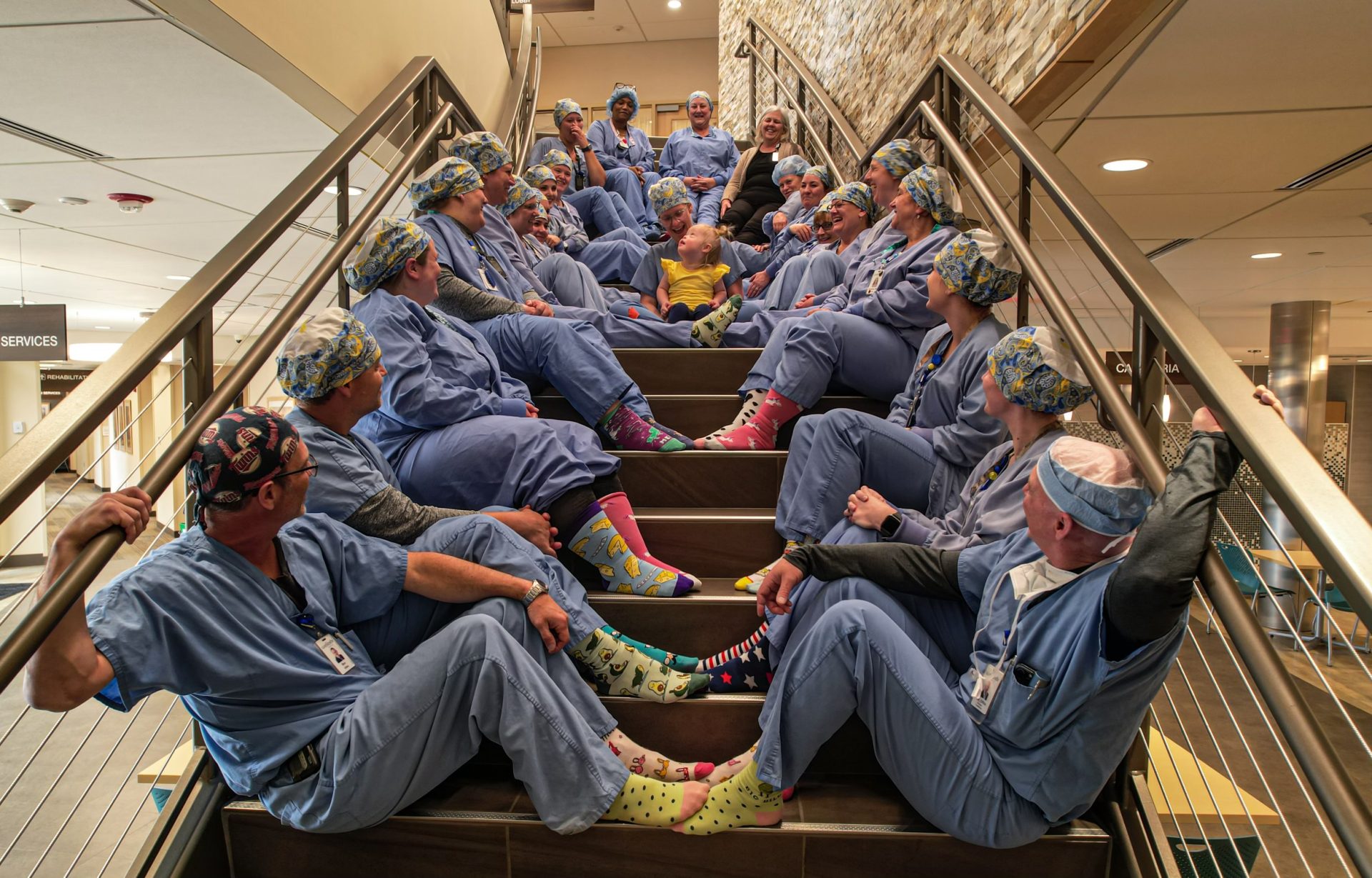 Welia Health OR team members sitting on a staircase with baby Amelia being held by her mother Rebecca