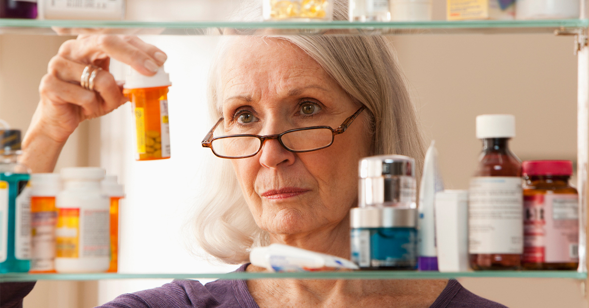Senior woman looking at a medicine cabinet filled with prescriptions