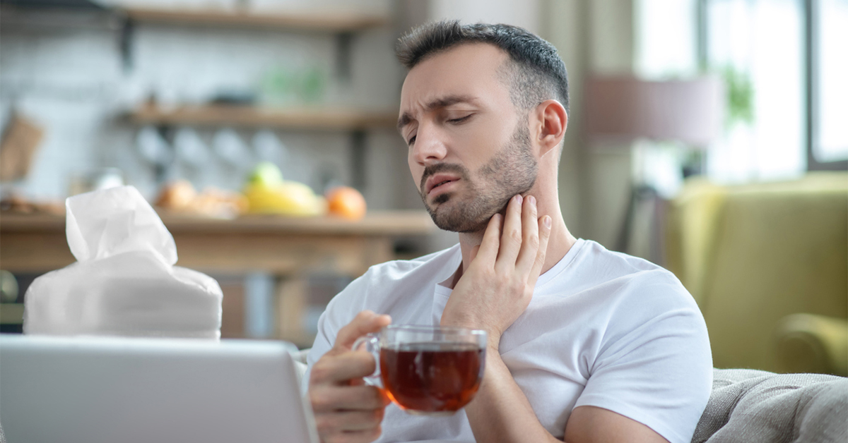 Man with sore throat drinking a cup of tea