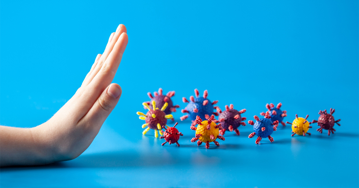A hand and artificial models of viruses on a blue background.