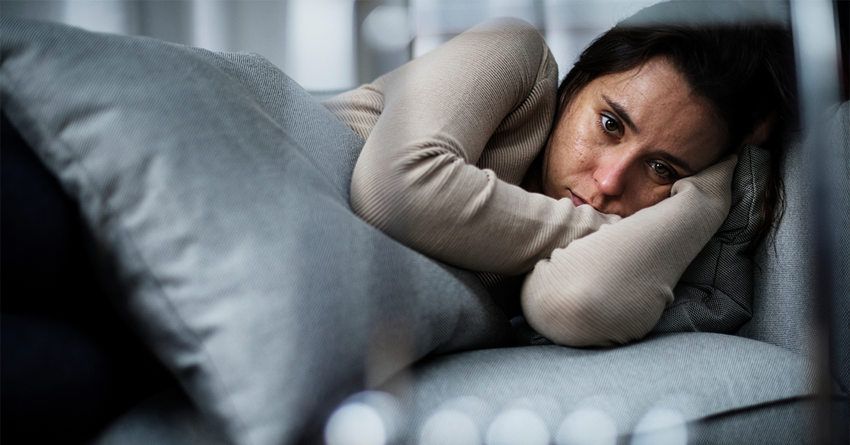 Young woman curled up with a pillow appearing depressed