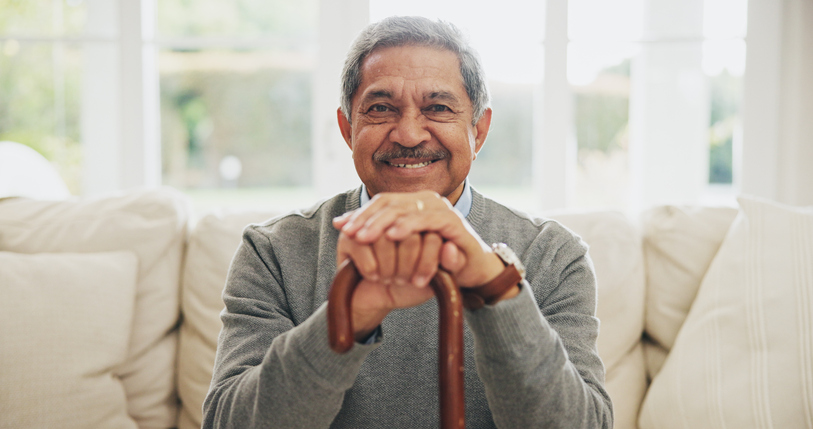 Senior man sitting on a couch and holding a cane