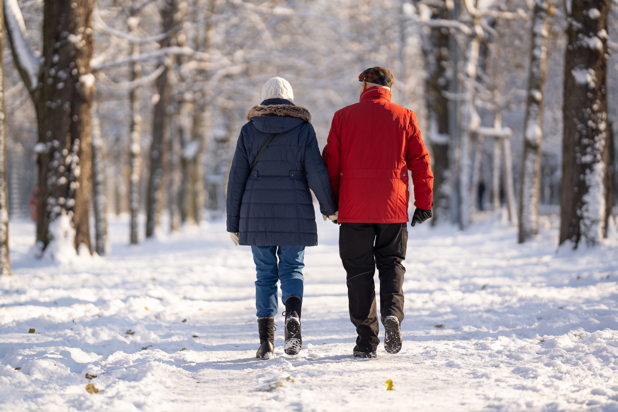  senior man and woman walking on snow covered path