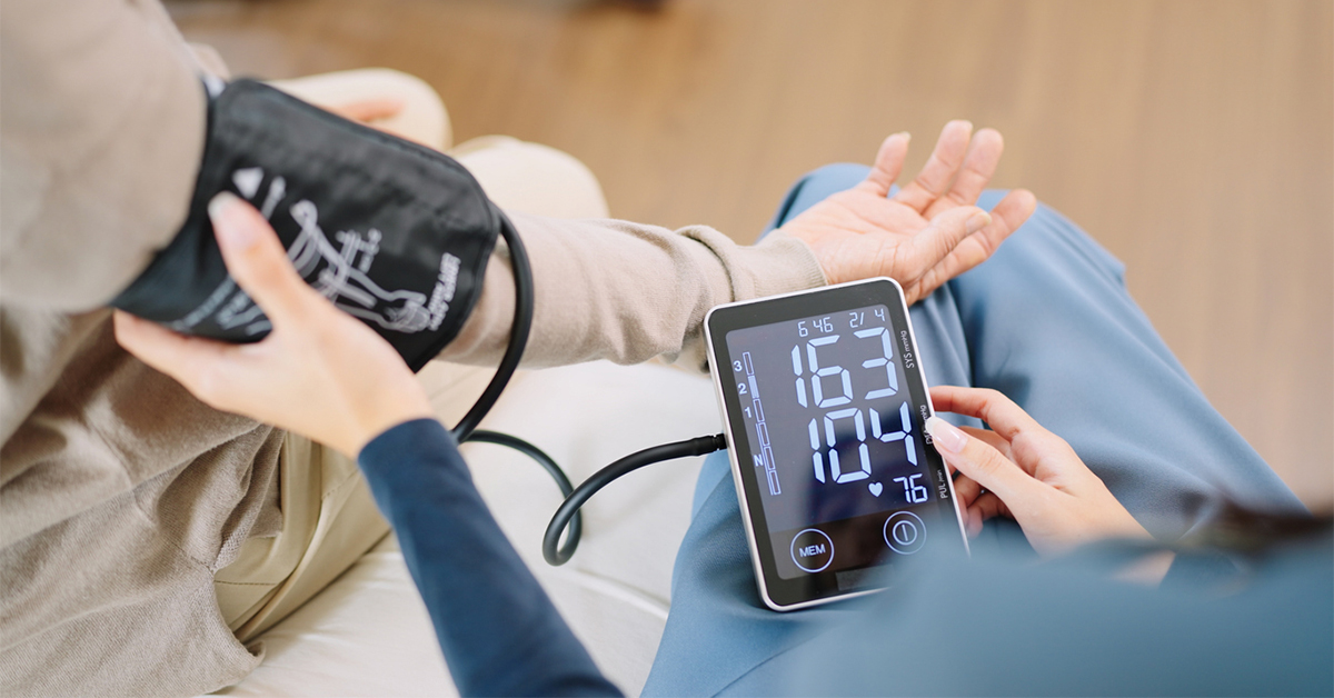 Individual getting their blood pressure checked. Electronic display shows high blood pressure.