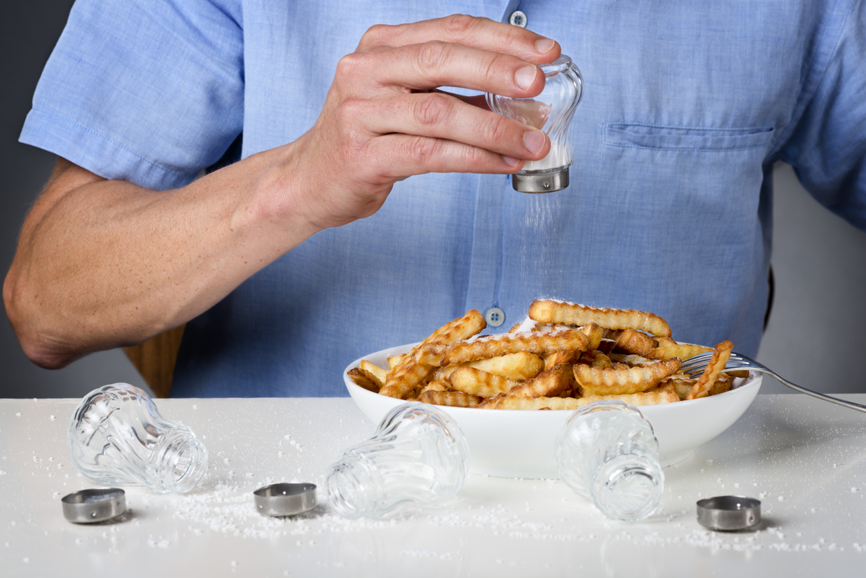 Man putting lots of salt on his french fries.