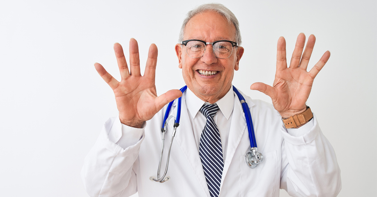 Doctor in lab coat with stethoscope holding up 10 fingers