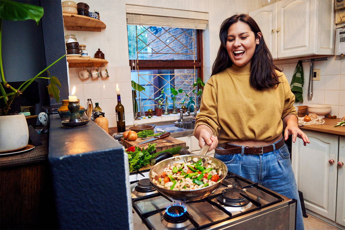 A woman in her kitchen cooking stir-fry on the stove