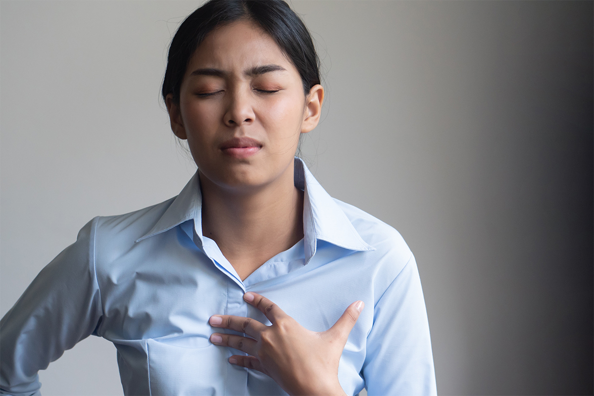 Young woman holding her chest from heartburn discomfort
