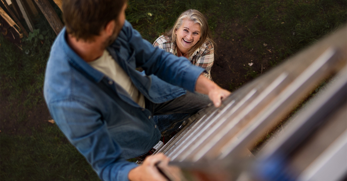 Man climbing a ladder with women standing by